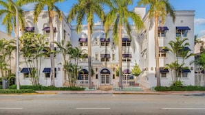 A multi-story hotel with a symmetrical facade, large windows, and a central entrance. - Aloha Fridays Miami Beach (Bal Harbour)