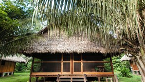 Une construction en bois, surmontée d’un toit de chaume, entourée d’une végétation luxuriante.