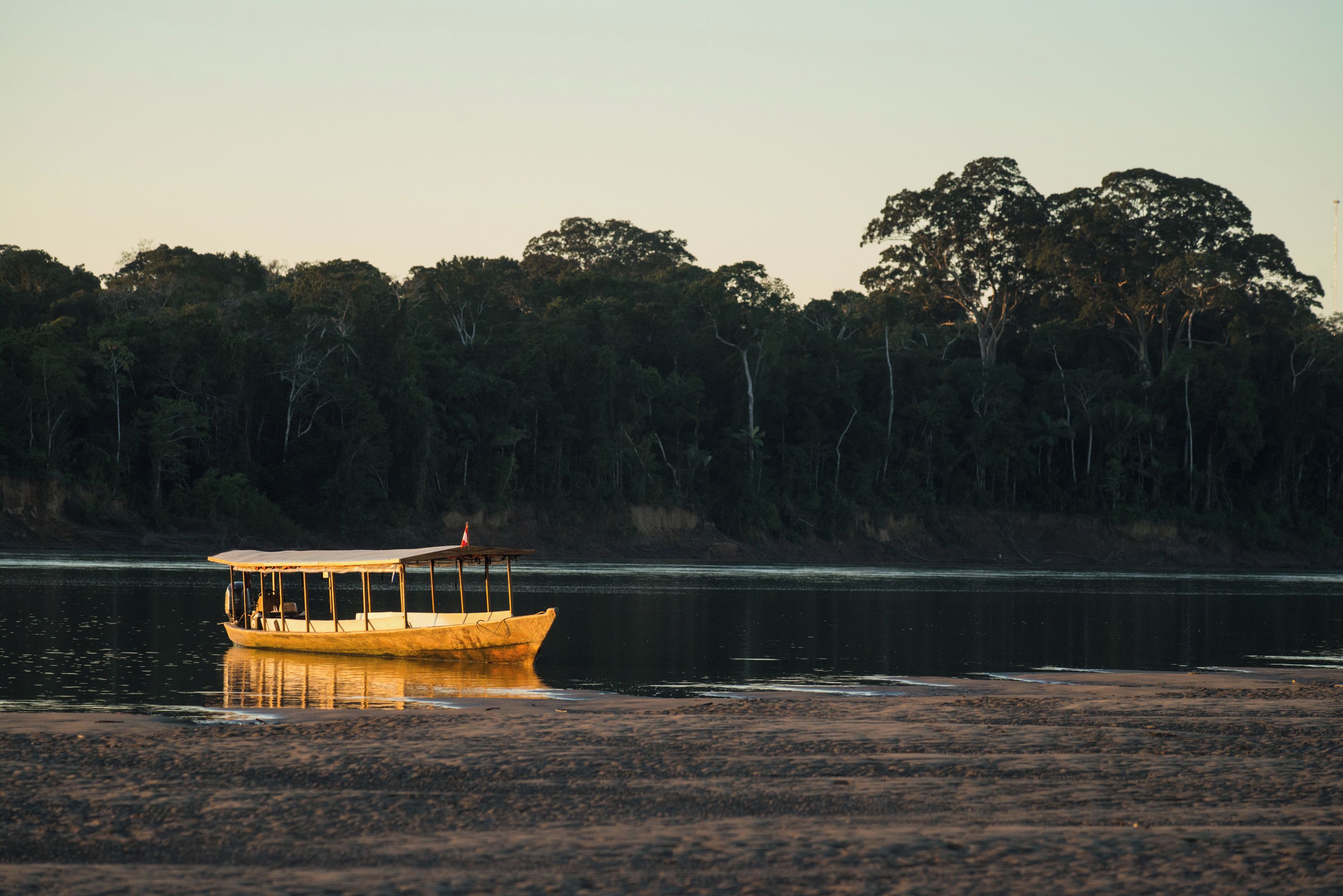 Um barco em um rio calmo com margens arborizadas.