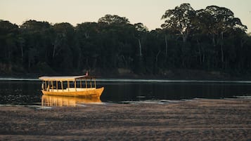 Um barco em um rio calmo com margens arborizadas.