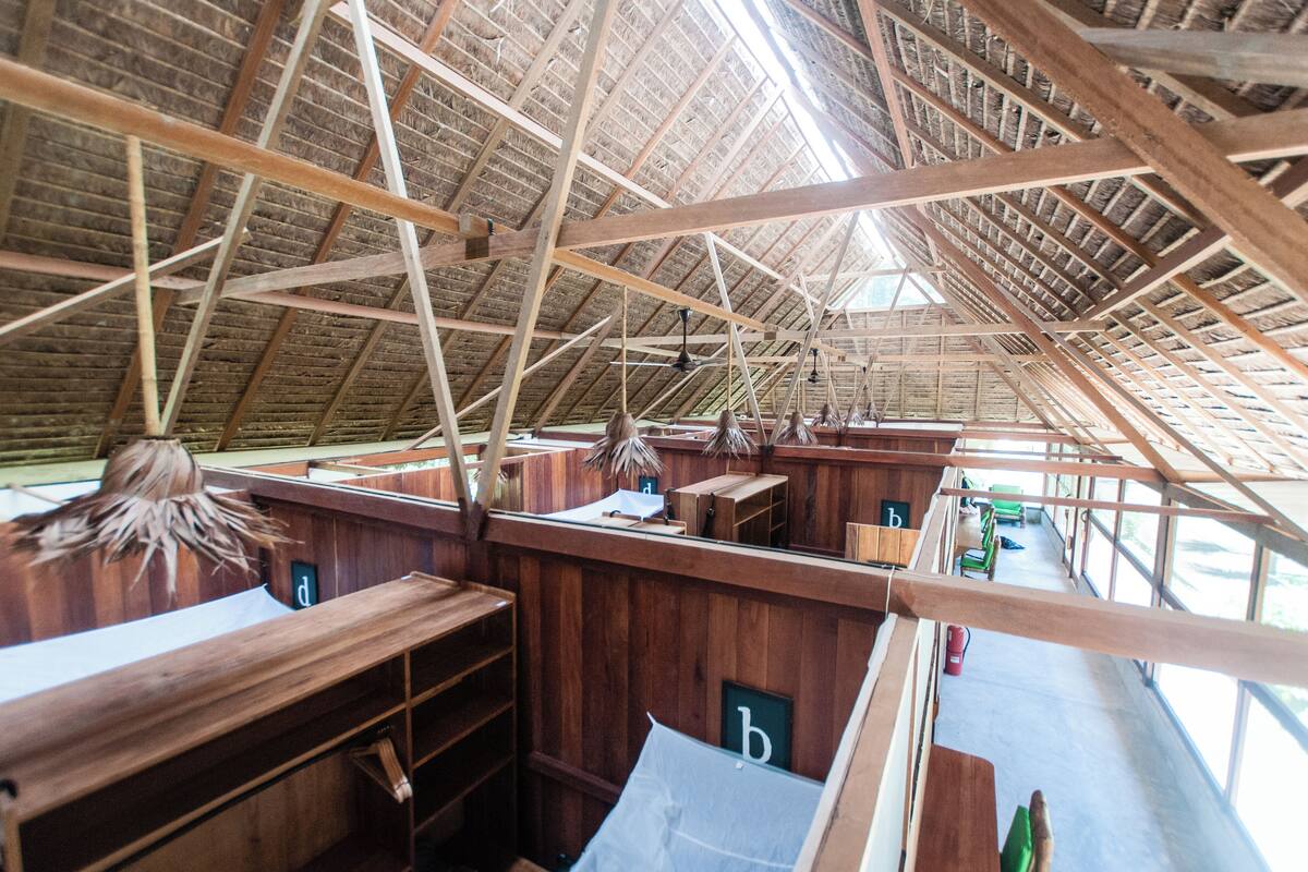An interior with a high, sloped wooden ceiling and multiple wooden benches.