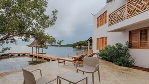 Une propriété située en bord de mer, dotée d’une terrasse en bois, de chaises longues et d’un abri au toit de chaume.