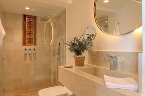 Un baño moderno con cabina de ducha de vidrio, un espejo grande y un lavabo con encimera blanca.