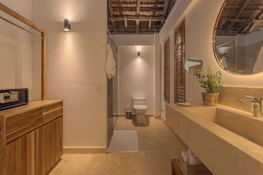 A modern bathroom with a wooden vanity, a round mirror, and a potted plant. - Soy Local Islawa (Cartagena)