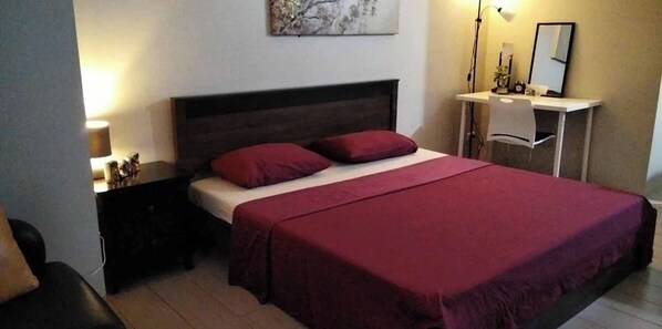 A bedroom with a bed, a nightstand, a desk, and a mirror. - 81 Newport Boulevard Across Naia T3 Airport (Pasay)