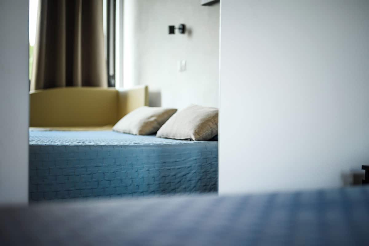 A bed with a blue mattress and two pillows.