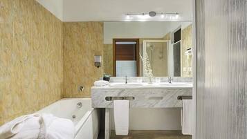 A bathroom with a marble vanity, a bathtub, and a large mirror.