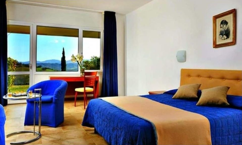 Una camera d'albergo con un letto, una scrivania, una sedia e vista sull'esterno.