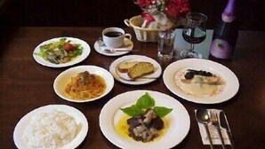 A table with various dishes, a cup of coffee, a bottle of wine, and a vase of flowers. - Pension Mori no Symphony (Shinano)