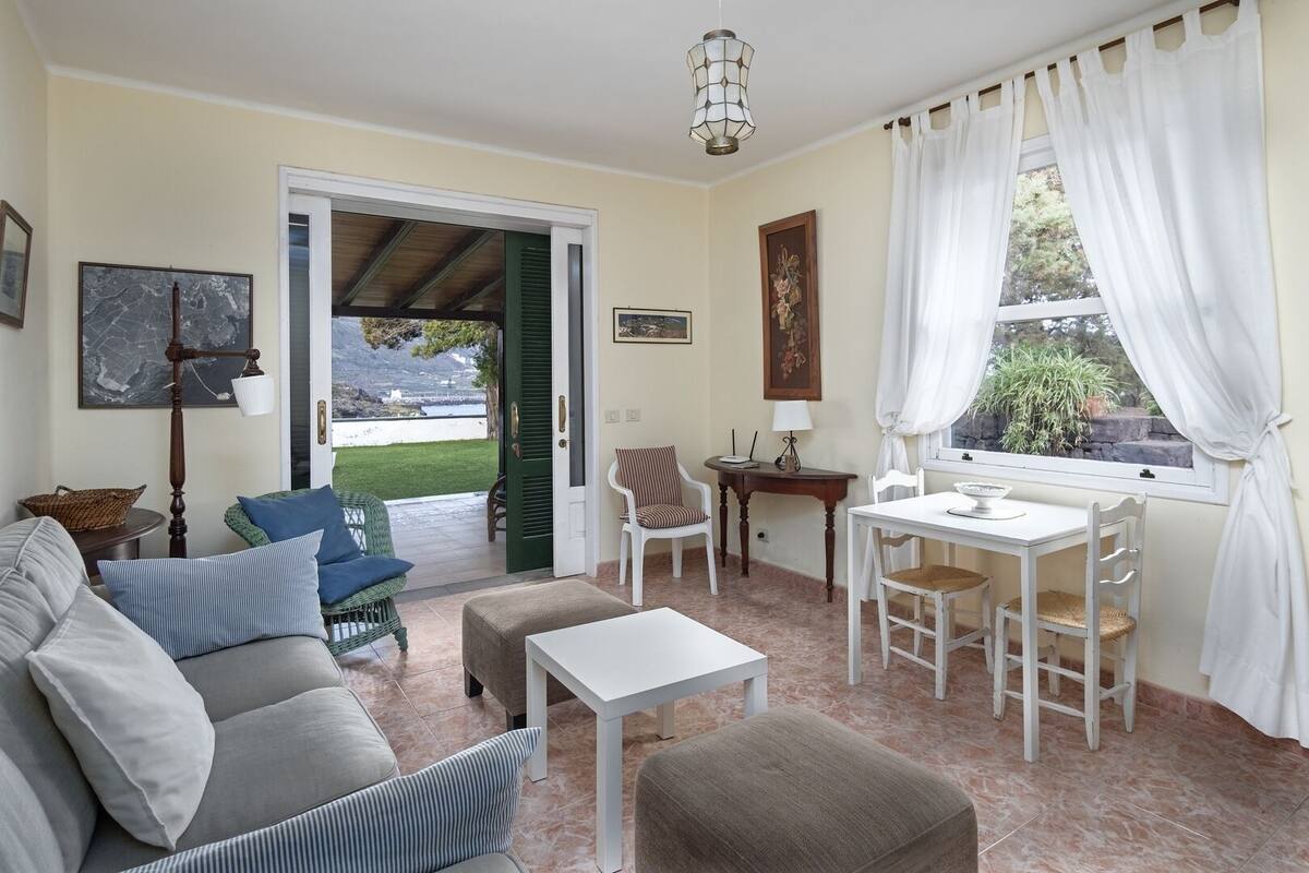 A living room with a sofa, chairs, a small table, and a window with curtains.