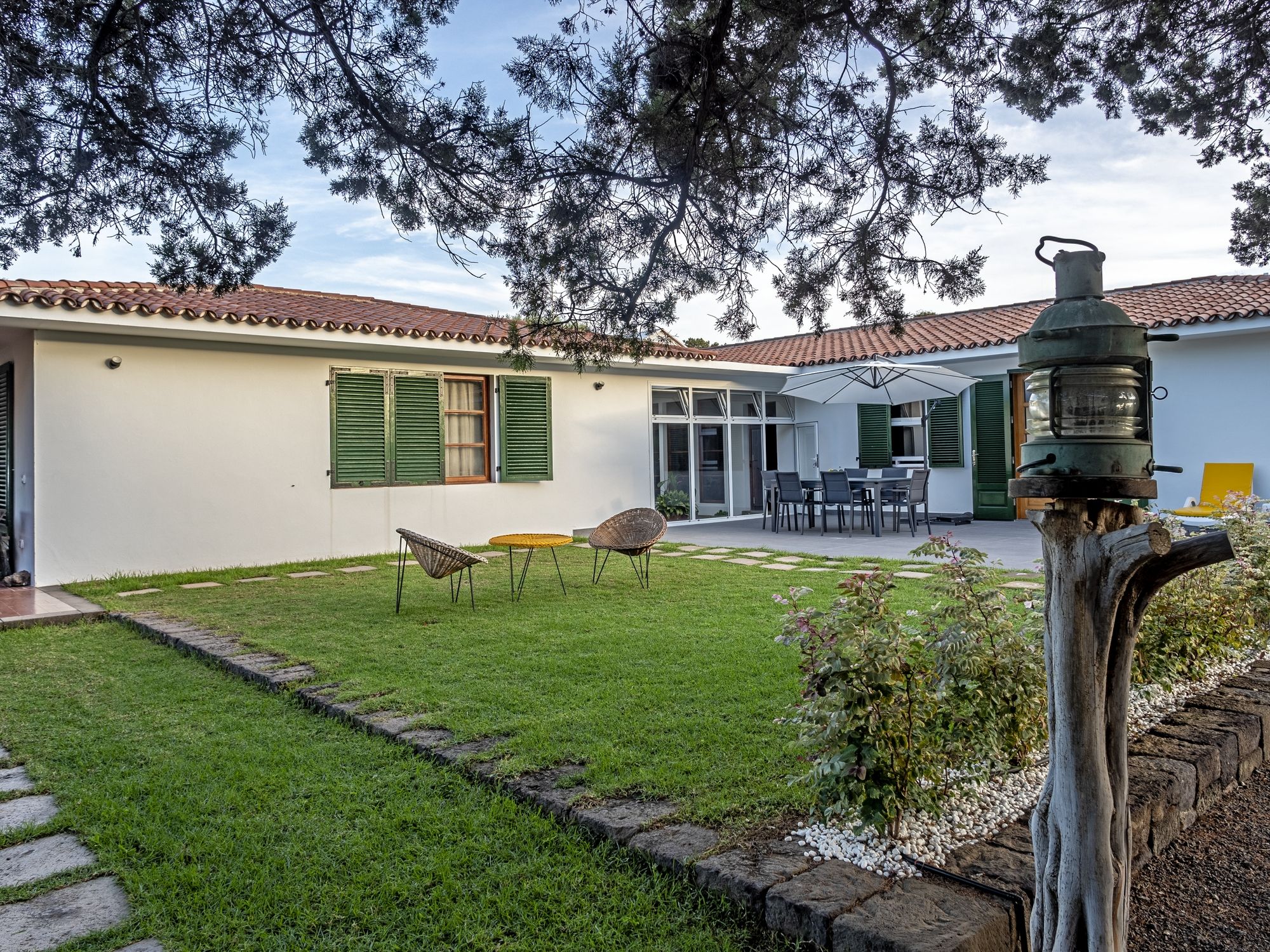 Une maison avec un patio, un coin repas et un jardin.