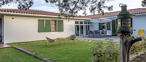Une maison avec un patio, un coin repas et un jardin.