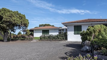 A two-story house with a gravel driveway and green shutters.
