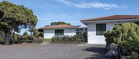 Una casa de dos pisos con entrada de grava y contraventanas verdes.