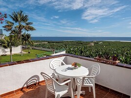 Una terraza con una mesa y sillas, con vistas a un paisaje costero.
