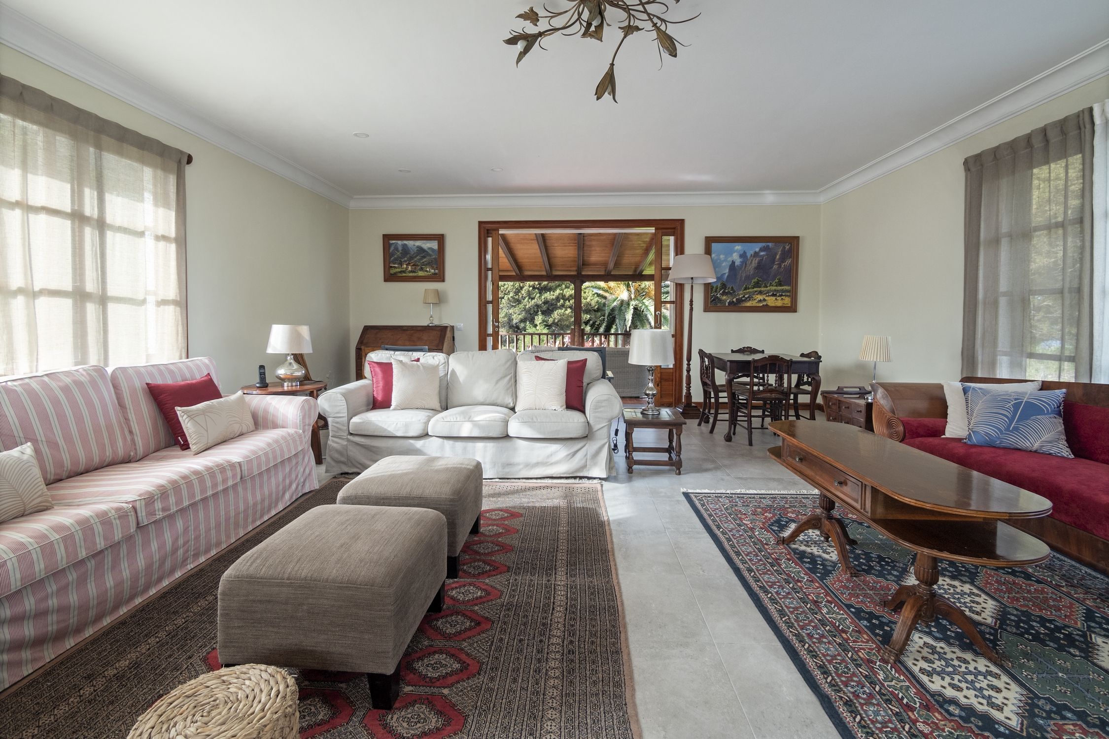 Amplia sala de estar con sofá, reposapiés, mesa de centro y comedor con sillas y mesa.