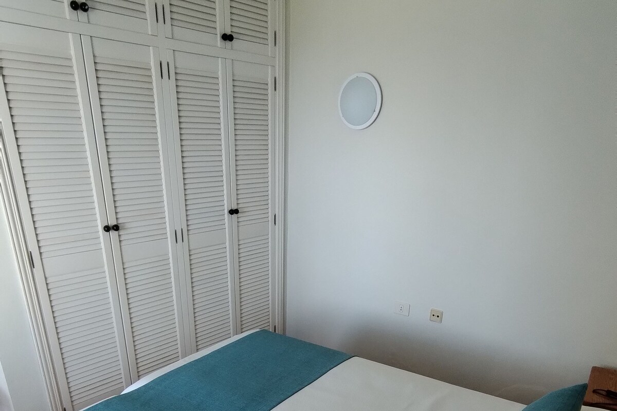 Ein Schlafzimmer mit einem Bett, einem Kleiderschrank und einer Wandleuchte.