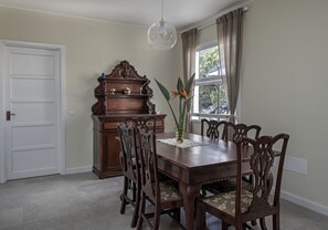 Ein Esszimmer mit Holztisch, sechs Stühlen, einem dekorativen Holzschrank und einer Vase mit Pflanze.