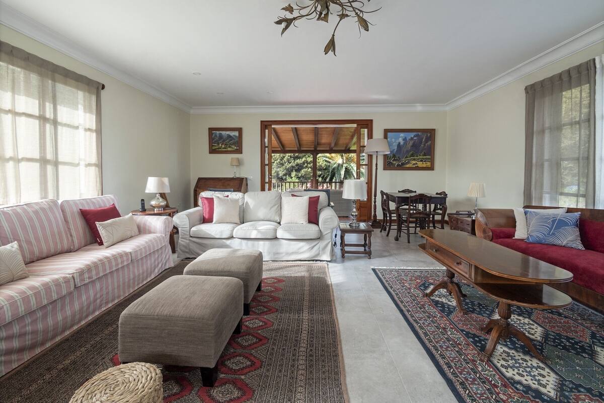 A spacious living room with a sofa, ottoman, coffee table, and a dining area with chairs and a table.