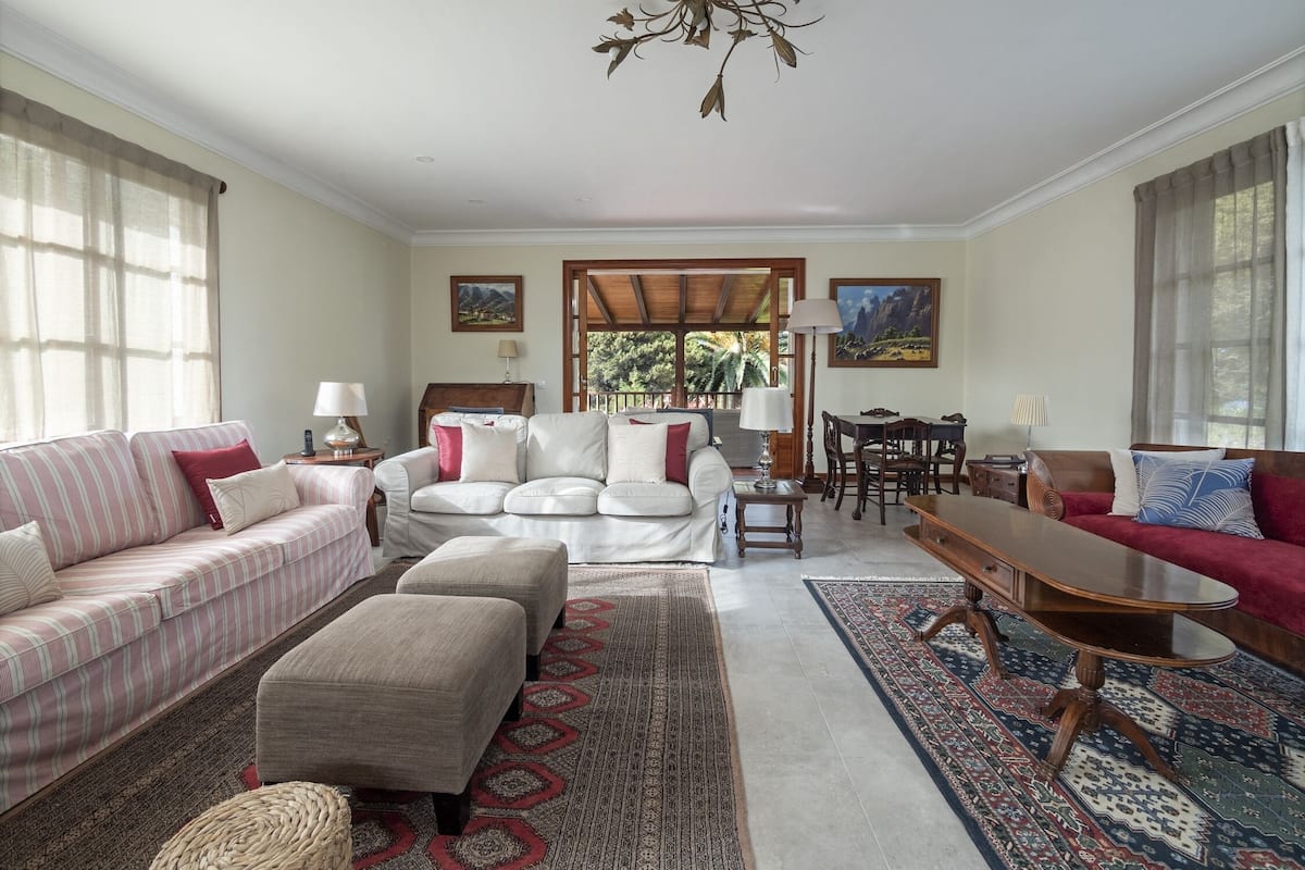 Un salon spacieux comprenant un canapé, un pouf, une table basse et un coin repas avec des chaises et une table.