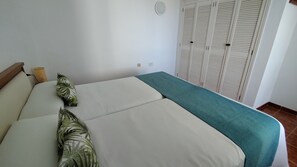 Ein Bett mit einer türkisfarbenen Decke, einem Holz-Kopfteil und zwei grünen Kissen.