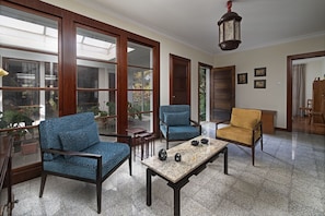 Una habitación amplia con ventanas grandes, una mesa de madera y dos sillas.