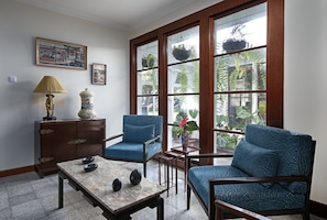 A room with a large window, two blue armchairs, a small table with decorative items, a cabinet, and a vase with flowers. - Sabinas & Terrazas Malpaís (Icod de los Vinos)