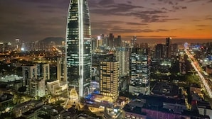A cityscape at night with a prominent curved skyscraper, surrounded by other high-rise buildings and illuminated streets. - Pagoda Hotel, Baoan,qianhai, Shenzhen (Shenzhen)