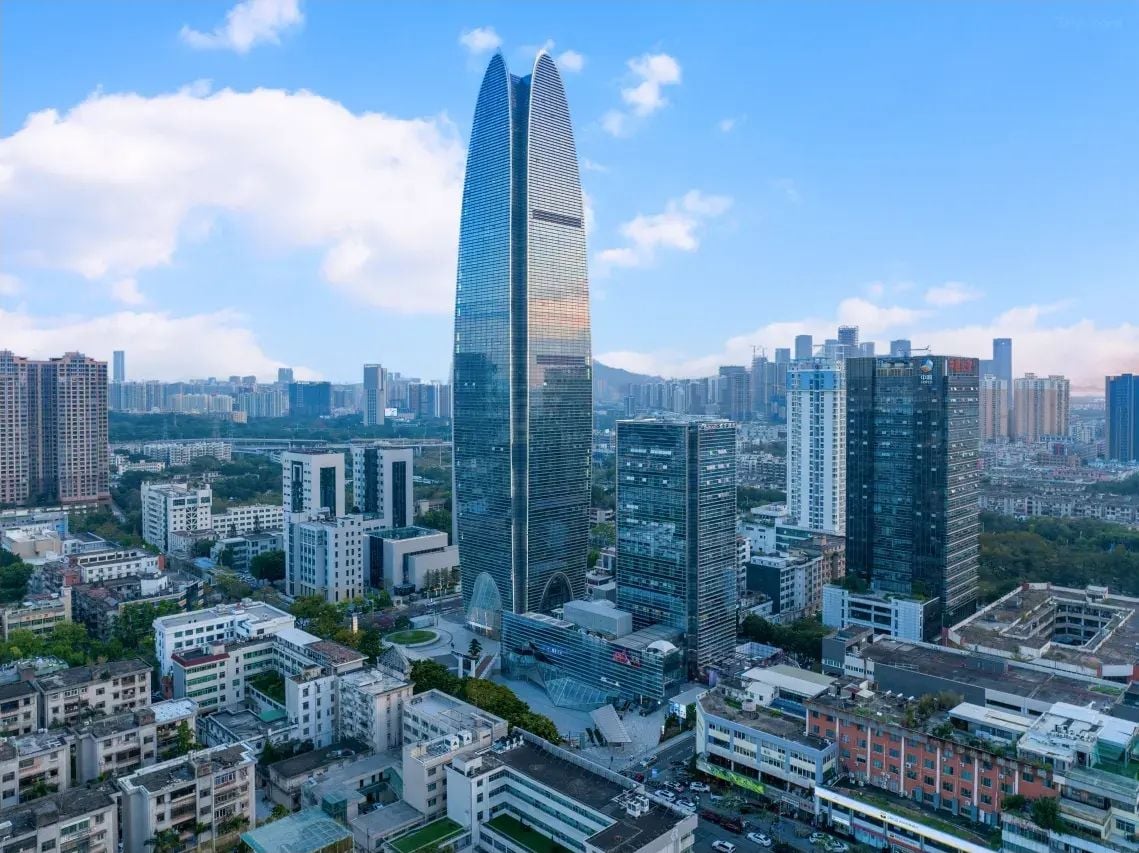A high-rise building with a sleek, modern design, surrounded by a dense urban environment with various other buildings.
