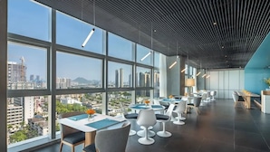 A modern dining area with large windows, contemporary chairs, and a city view. - Pagoda Hotel, Baoan,qianhai, Shenzhen (Shenzhen)