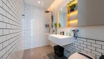 A modern bathroom with white subway tiles, a white sink, and a mirror with a shelf above it.