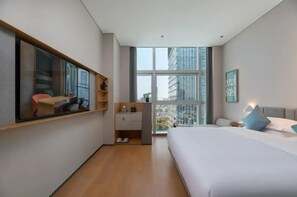 A modern hotel room with a large bed, a desk with a chair, a small kitchenette, and a large window offering a city view. - Pagoda Hotel, Baoan,qianhai, Shenzhen (Shenzhen)
