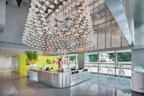 A modern hotel lobby with a central reception desk, large windows, and a ceiling adorned with hanging white umbrellas. - Pagoda Hotel, Baoan,qianhai, Shenzhen (Shenzhen)