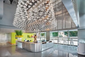 A modern hotel lobby with a central reception desk, large windows, and a ceiling adorned with hanging white umbrellas. - Pagoda Hotel, Baoan,qianhai, Shenzhen (Shenzhen)