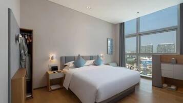 A modern bedroom with a large bed, bedside tables, a wardrobe, and a city view through large windows.