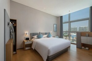 A modern bedroom with a large bed, bedside tables, a wardrobe, and a city view through large windows. - Pagoda Hotel, Baoan,qianhai, Shenzhen (Shenzhen)