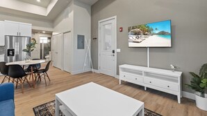 A modern living room with a dining area, a flat-screen TV, and a white console table. - Modern Apartment + Balcony (Fort Collins)