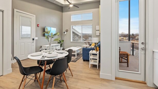 A modern living room with a dining area, a blue sofa, and a balcony with a view. - Modern Apartment + Balcony (Fort Collins)