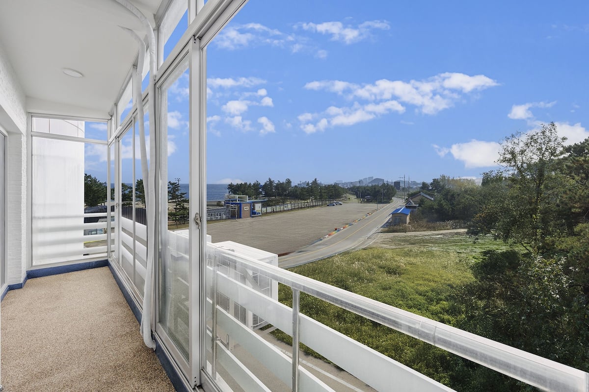 A balcony with a view of a parking lot and greenery.
