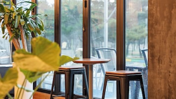 Un interior de restaurante con un ventanal grande, una mesa redonda y dos sillas.
