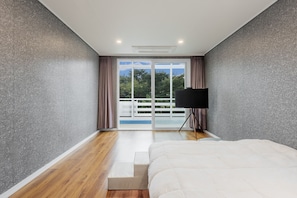 Un dormitorio con una cama, un televisor sobre un mueble bajo, una puerta corrediza de vidrio que da a un balcón y una escalera.