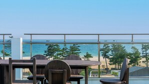A terrace with a view of the sea, featuring wooden tables and chairs. - Goseong Mung Stay (Goseong)