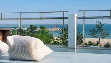 Una habitación con vista a una playa, un faro y un promontorio rocoso.