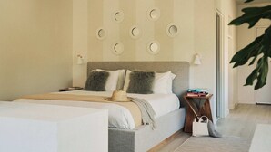 Quarto com cama, mesas de cabeceira e parede decorada com detalhes circulares.