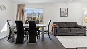 A modern living room with a dining area, a grey sofa, a white rug, and a painting on the wall. - Fantastic Family Lakehouse - Room for everyone (Mangakino)