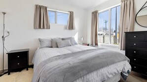 A bedroom with a large bed, two bedside tables, a dresser, and a window with curtains. - Fantastic Family Lakehouse - Room for everyone (Mangakino)