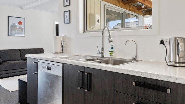 A modern kitchen with a dishwasher, double sink, and a large window above the counter. - Fantastic Family Lakehouse - Room for everyone (Mangakino)