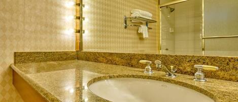 A bathroom with a granite countertop sink, a mirror, and a towel rack with folded towels.