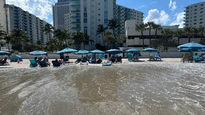 Una playa con agua, sombrillas y gente.