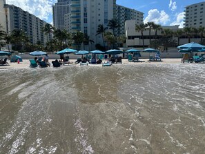 A beach with water, umbrellas, and people. - Luxuriously Remodeled Beachfront Condo • Heated Pool (Hollywood)